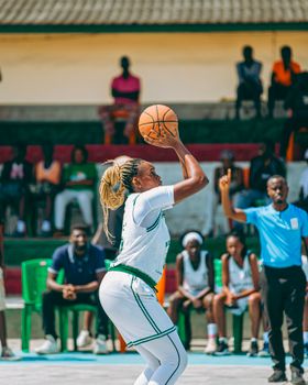 A focused female athlete prepares to shoot a basketball during an outdoor game.