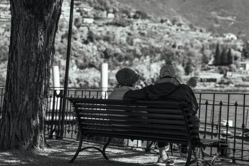 Free Serene moment of an elderly couple on a bench overlooking Lake Como. Stock Photo