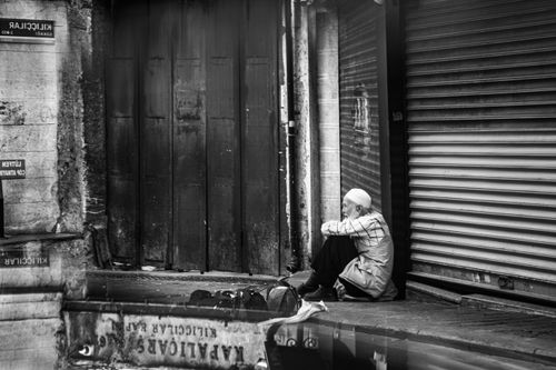 Free A contemplative moment of a man sitting in an Istanbul alleyway, captured in black and white. Stock Photo