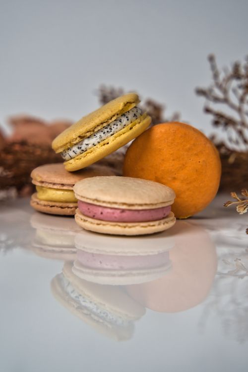 Free Artistic presentation of colorful French macarons with various fillings on a mirrored surface. Stock Photo