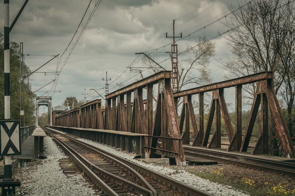 NordPass vs Bitwarden: Autofill Sync Showdown A rustic iron railway bridge crossing train tracks under a cloudy sky.
