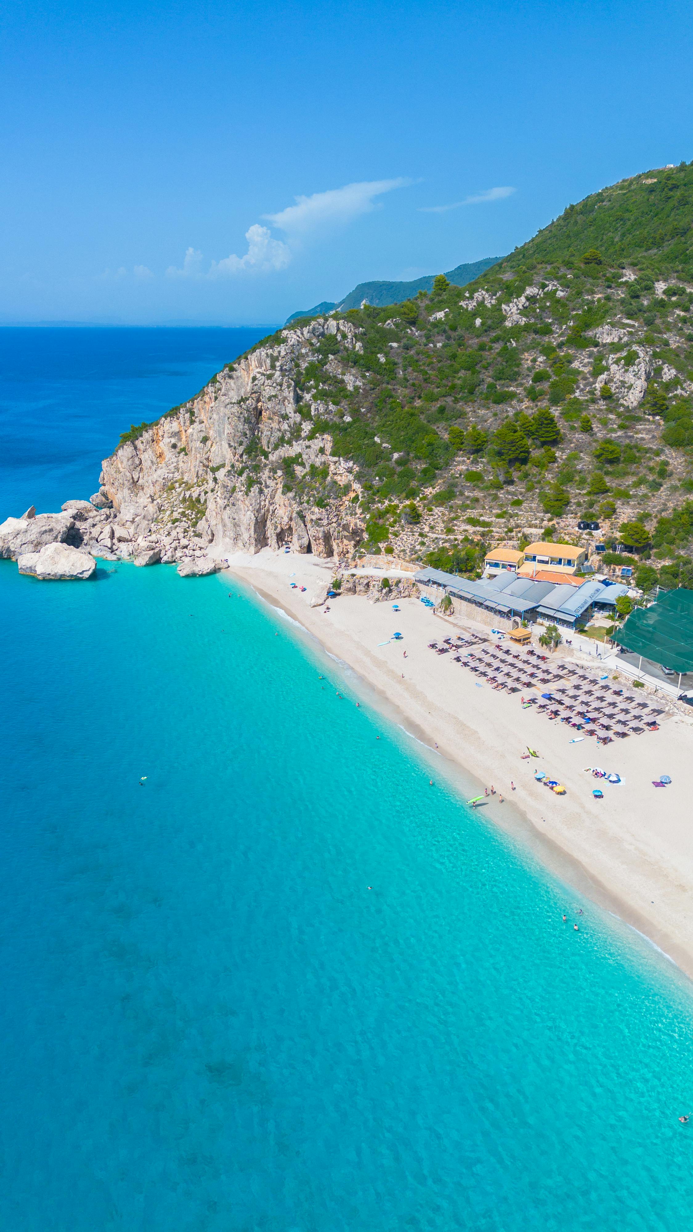 Stunning aerial shot of a tranquil beach with turquoise water and rocky cliffs, perfect summer escape.