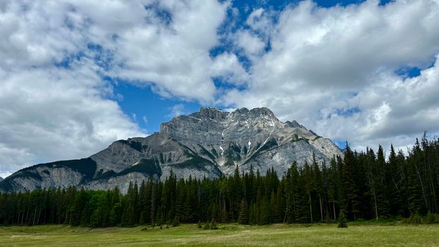 Stunning view of a mountain with lush forest in Banff National Park under a cloudy sky.