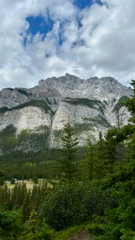 Breathtaking view of a rocky mountain range amidst lush greenery and a vibrant sky.