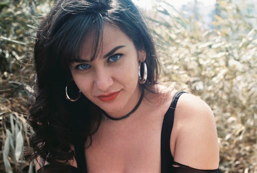 Close-up portrait of a young woman with hoop earrings outdoors.