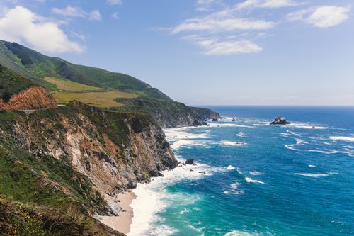 Free Dramatic coastal cliffs of Monterey, California against a vibrant ocean under a blue sky. Stock Photo