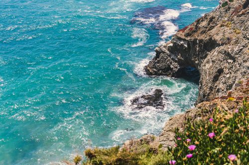 Free Vibrant ocean waves crashing against rocky cliffs in Monterey, California's stunning coastline. Stock Photo
