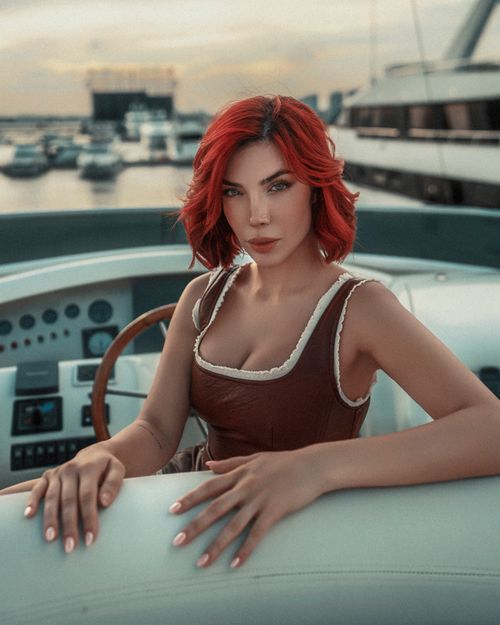 Free Elegant woman with red hair on a luxury yacht at Dubai Marina during sunset. Stock Photo