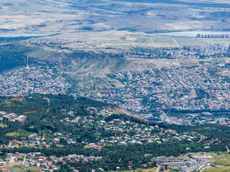 A breathtaking aerial view of Tbilisi, showcasing its urban landscape and surrounding hills in the summer.