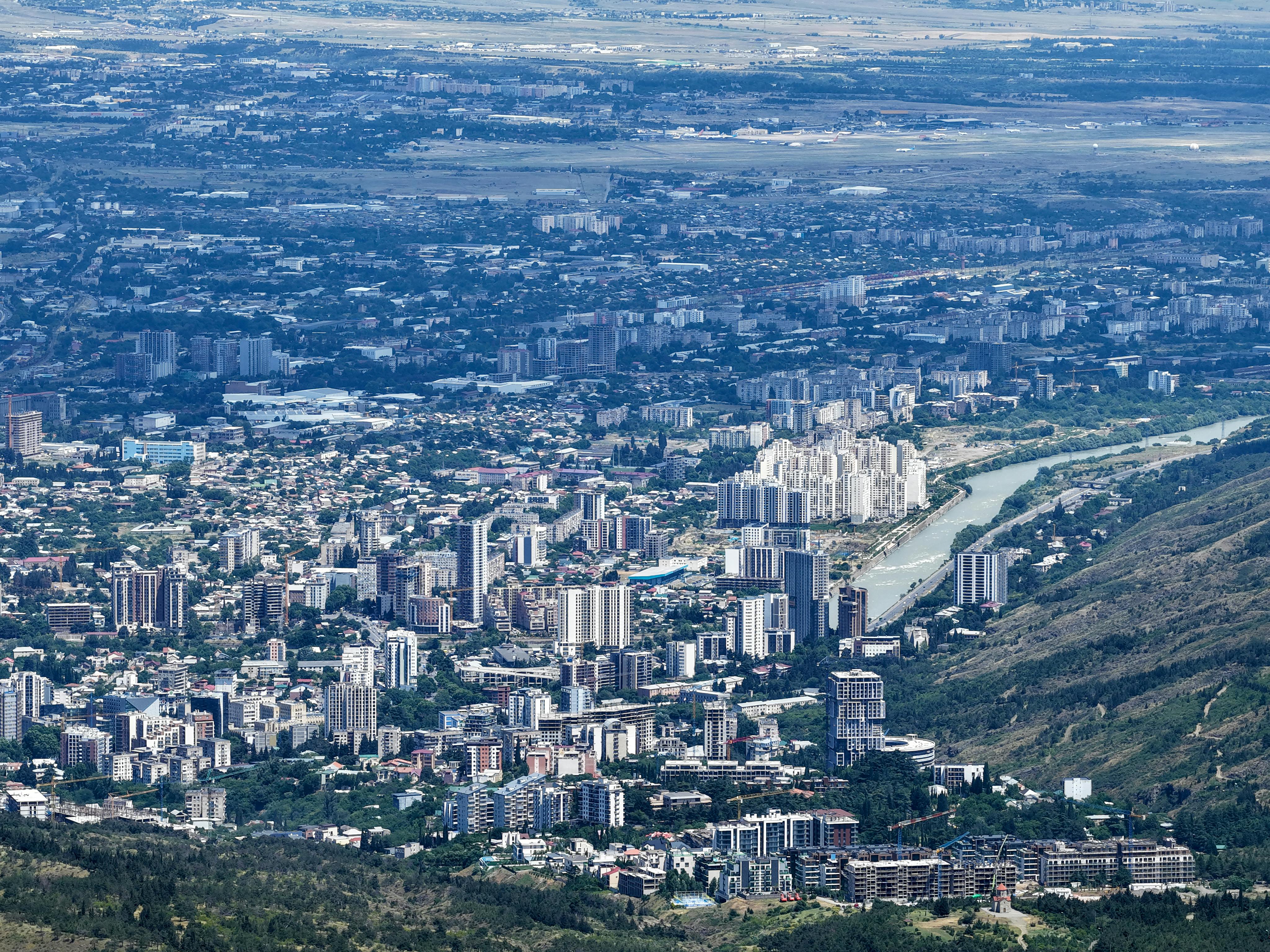 Expansive aerial view of the vibrant cityscape of Tbilisi, Georgia, featuring urban architecture and lush landscapes.