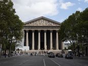 A frontal view of La Madeleine Church in Paris, showcasing its classic architecture on a bright day.