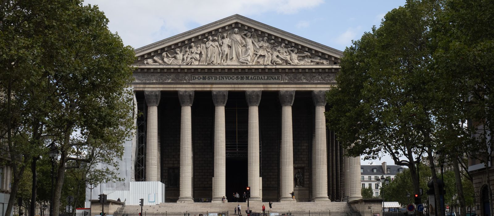 A frontal view of La Madeleine Church in Paris, showcasing its classic architecture on a bright day.