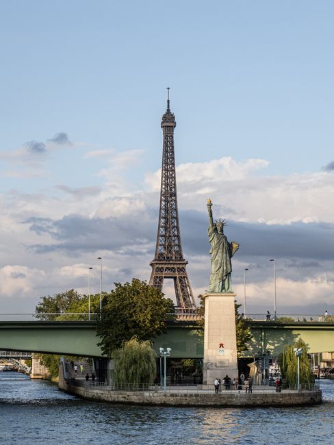 View of the Eiffel Tower and the Statue of Liberty on Île aux Cygnes in Paris during the day.