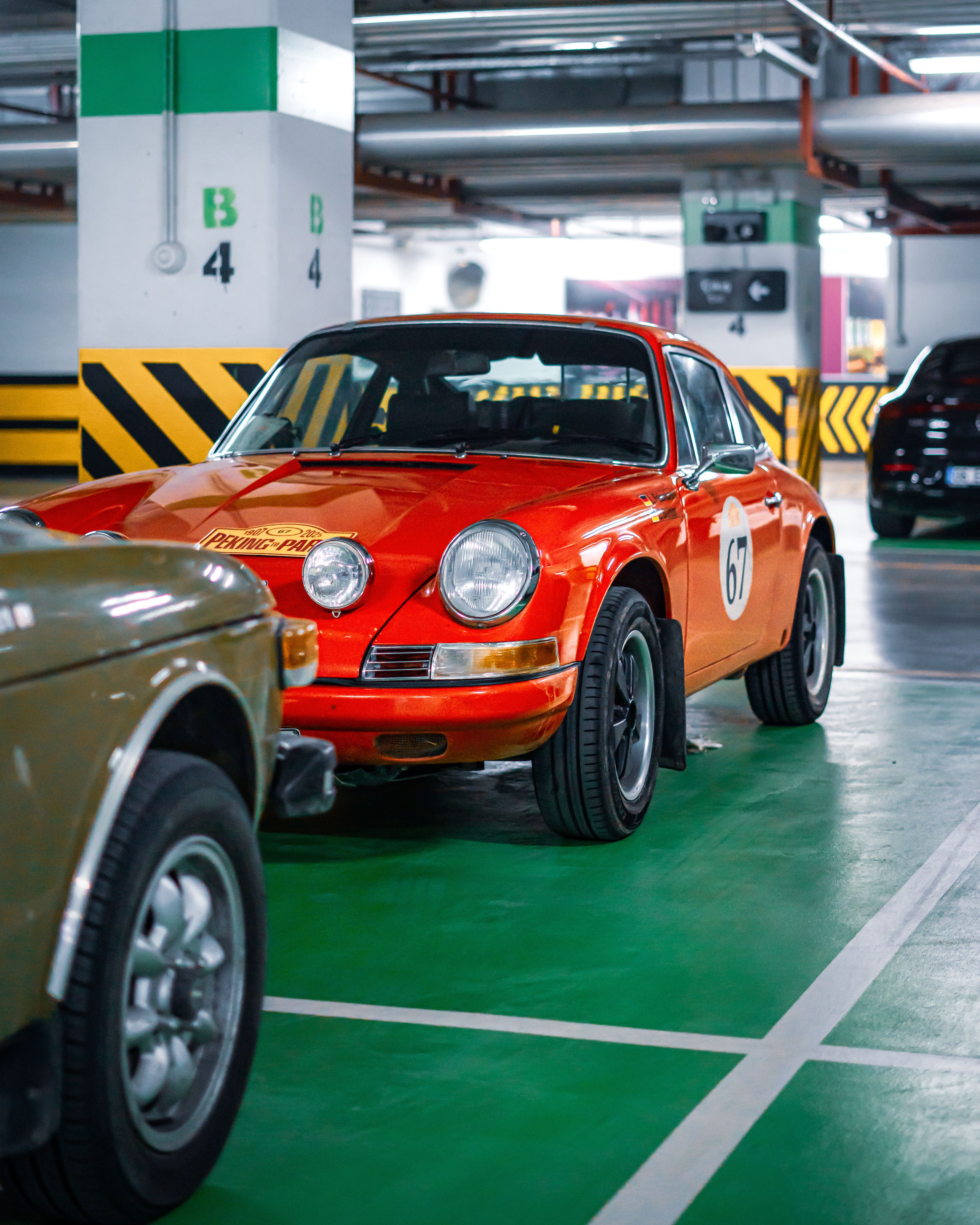 Vintage red Porsche parked in a well-lit indoor garage with numbered columns.