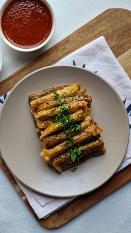 Free Delicious stuffed grape leaves garnished with herbs, served with a side of rich tomato sauce. Stock Photo