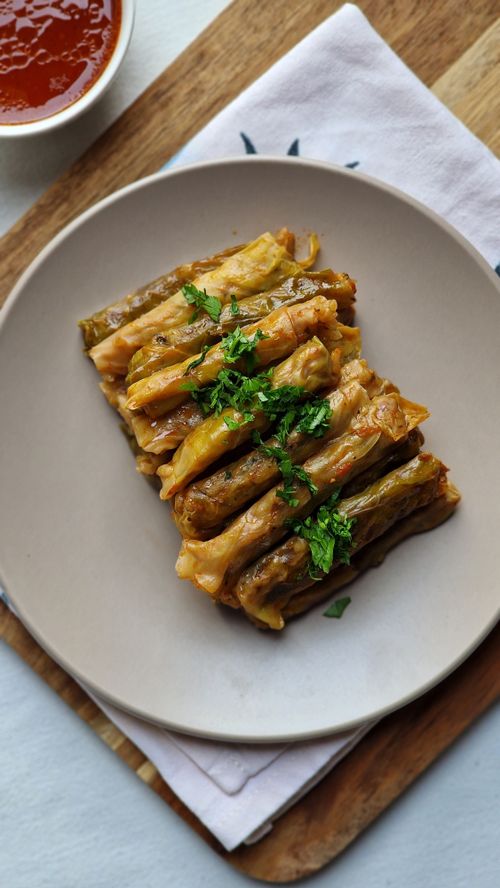 Free Delicious sarmale served with a side dish of tomato sauce, garnished with fresh herbs. Stock Photo
