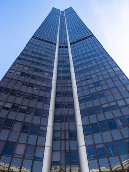 Impressive view of a towering skyscraper with glass facade reaching towards the clear blue sky, symbolizing modern architecture.
