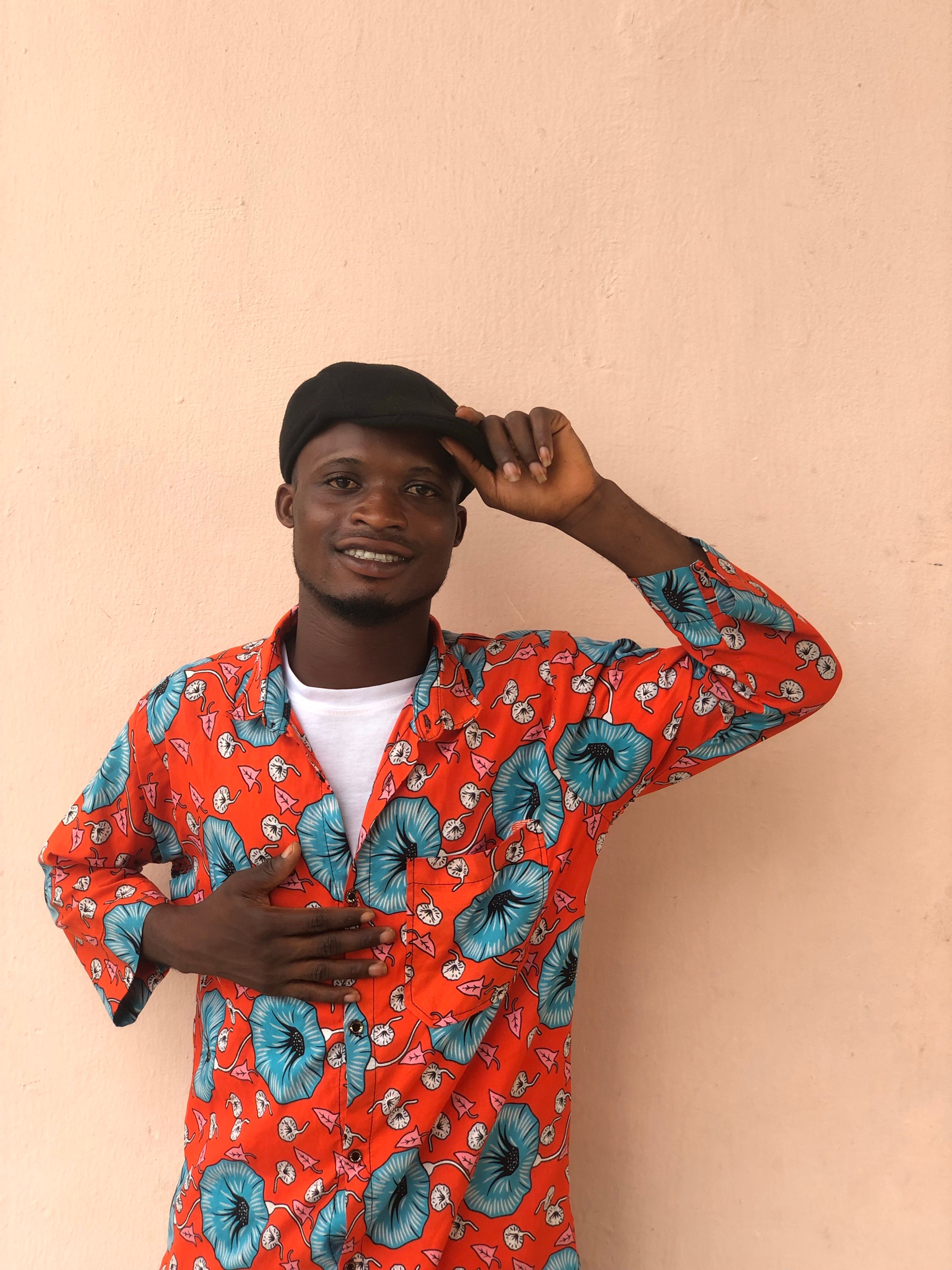 Cheerful man in vibrant African print shirt posing against a plain background.