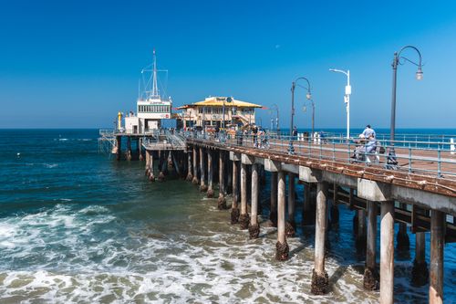 Free A vibrant view of Santa Monica Pier extending over the ocean under a clear blue sky. Stock Photo