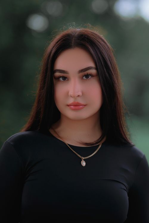 Free A serene outdoor portrait of a woman in a black dress, exuding elegance and poise. Stock Photo