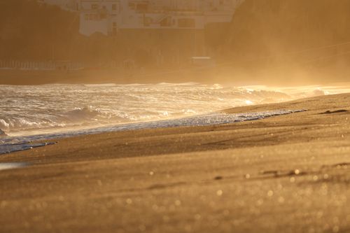 Free A serene beach at sunset with golden waves crashing on the shore, creating a dreamy atmosphere. Stock Photo