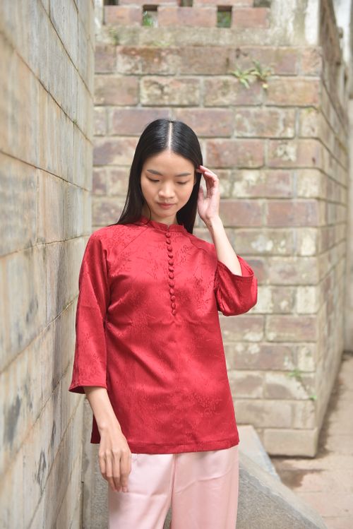 Free A poised woman in a red traditional outfit poses outdoors against a brick wall. Stock Photo