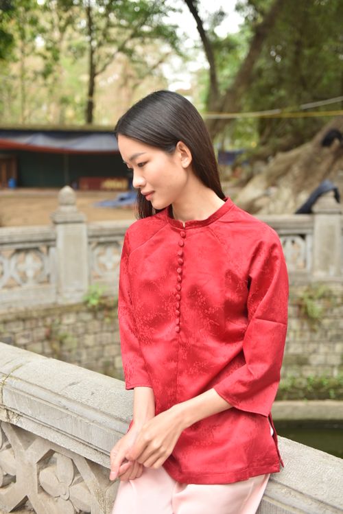 Free Young woman in a traditional red dress standing on a bridge in a serene outdoor setting. Stock Photo
