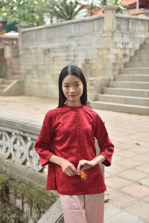 Free A woman in a red traditional outfit poses gracefully outdoors in an architectural setting. Stock Photo