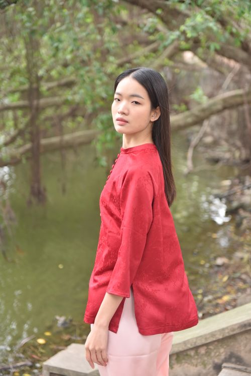 Free A serene portrait of a young woman in a red outfit by a peaceful outdoor pond. Stock Photo