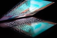 特写镜头下的现代笔记本电脑，键盘发光，屏幕反射出彩色光芒