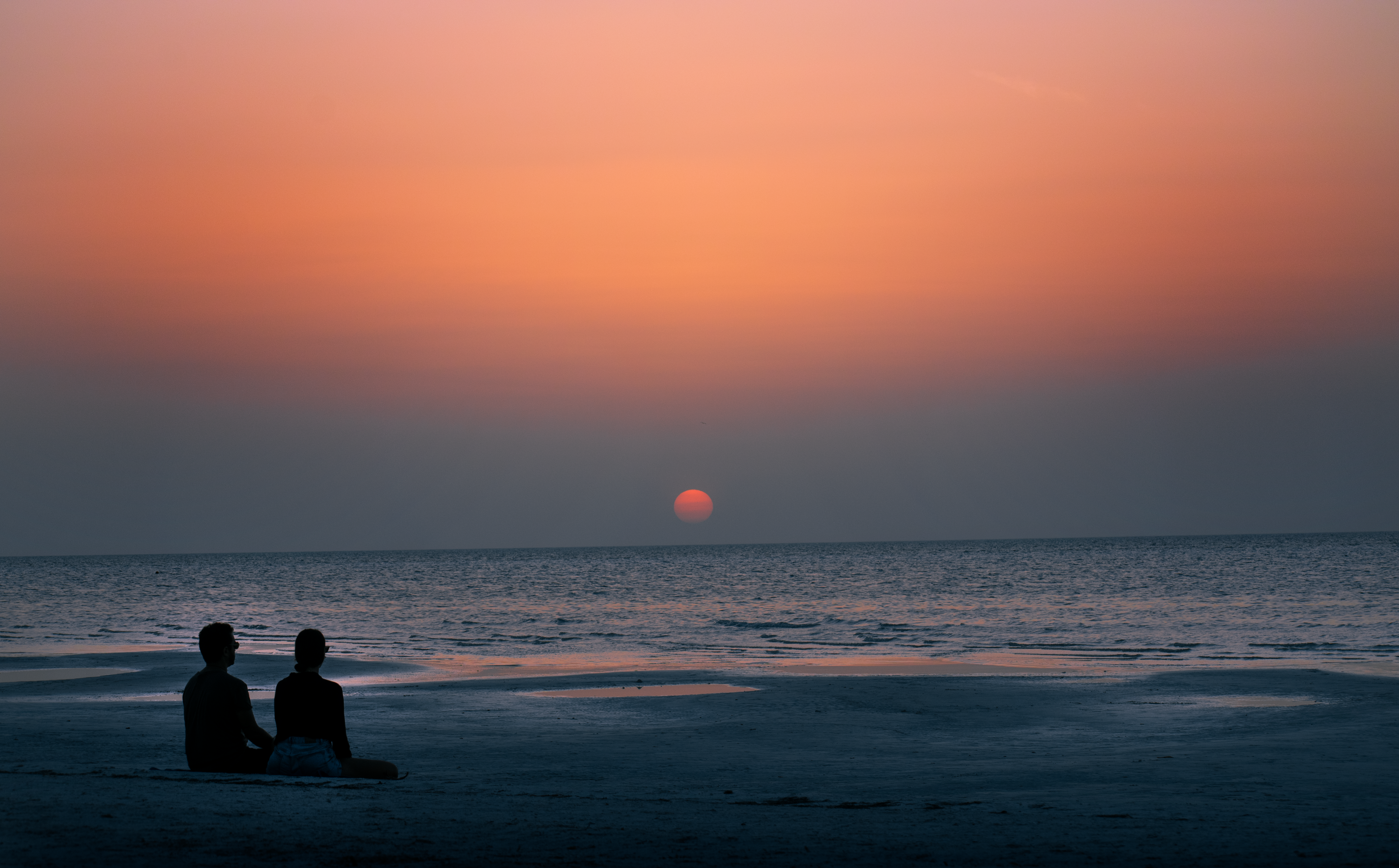 A serene sunset on Holbox beach, Mexico, with a couple enjoying the tranquil view. A serene sunset on Holbox beach, Mexico, with a couple enjoying the tranquil view.