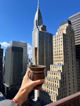 Hand holding a mate cup with the iconic Chrysler Building in the background.