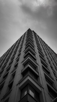 Striking low-angle view of a skyscraper against a moody sky, in black and white.