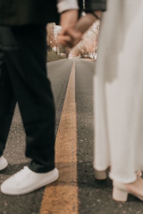 Free Blurred couple holding hands on deserted road, symbolizing unity and journey. Stock Photo
