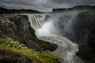 在多云的天空下，瀑布从陡峭的岩壁上倾泻而下，景象十分壮观