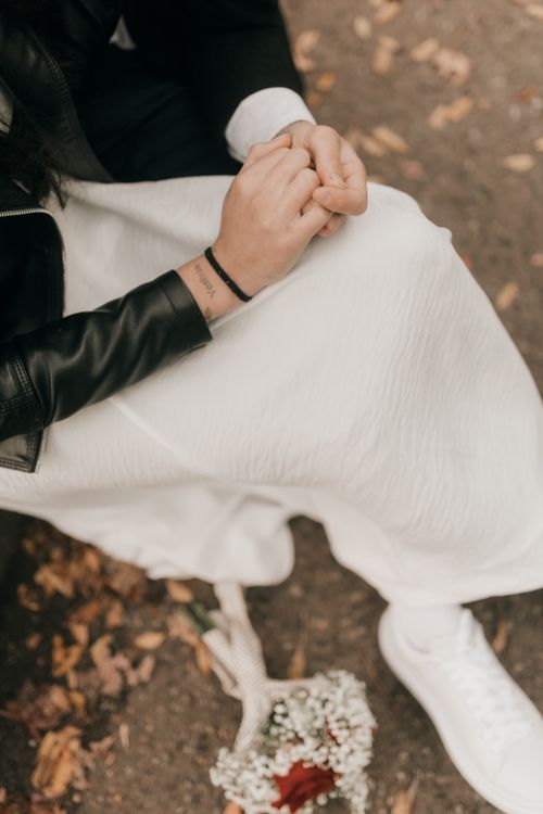 Free Close-up of a woman in a white dress holding a bouquet with fallen leaves on the ground. Stock Photo