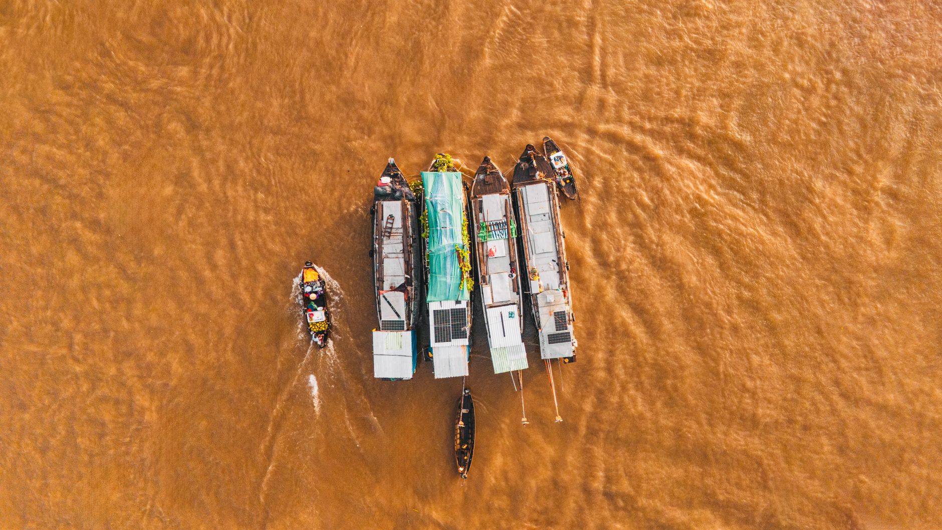 A dynamic aerial shot of boats congregating at Cái Răng Floating Market in Cần Thơ, Vietnam.