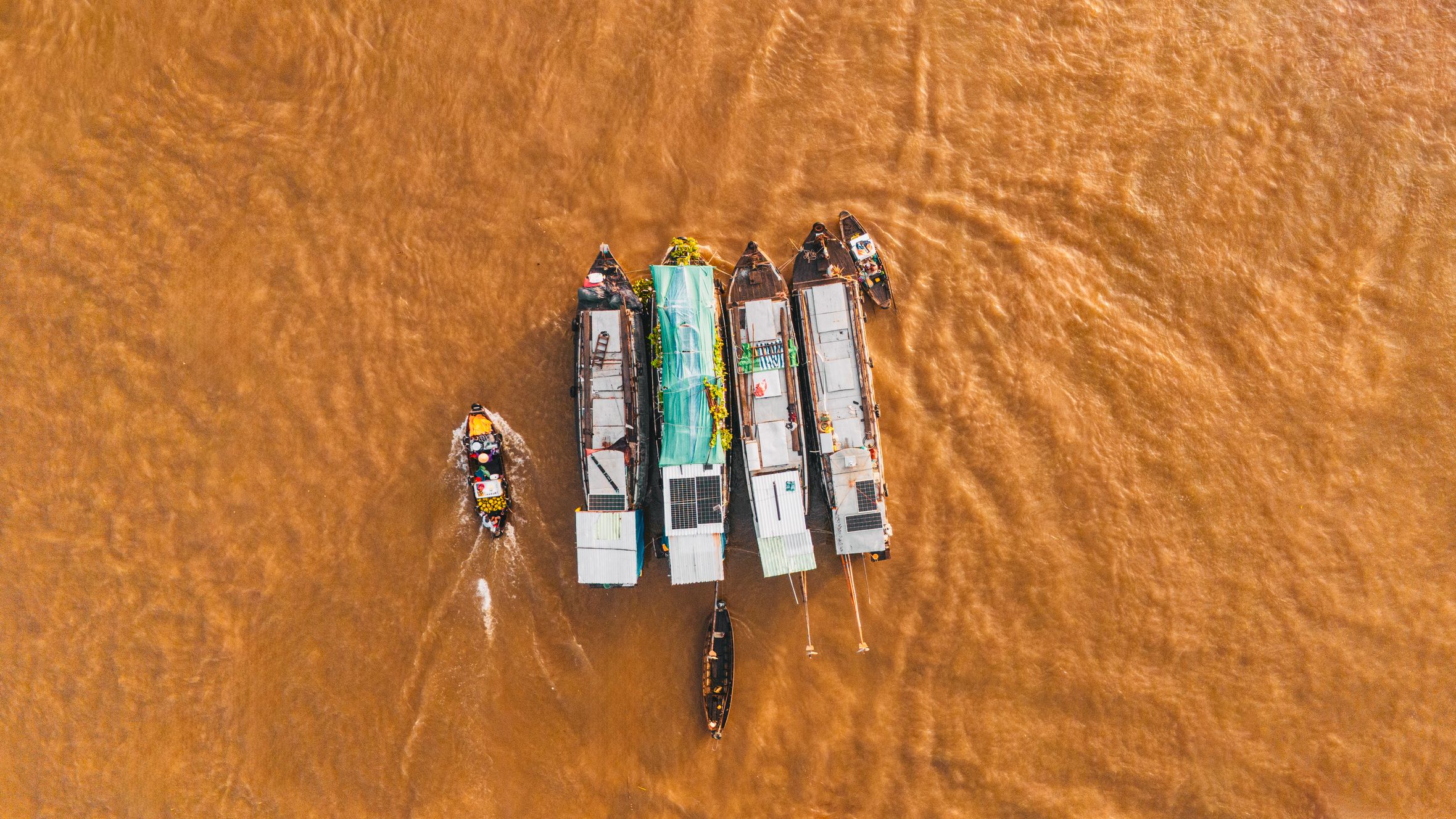A dynamic aerial shot of boats congregating at Cái Răng Floating Market in Cần Thơ, Vietnam.