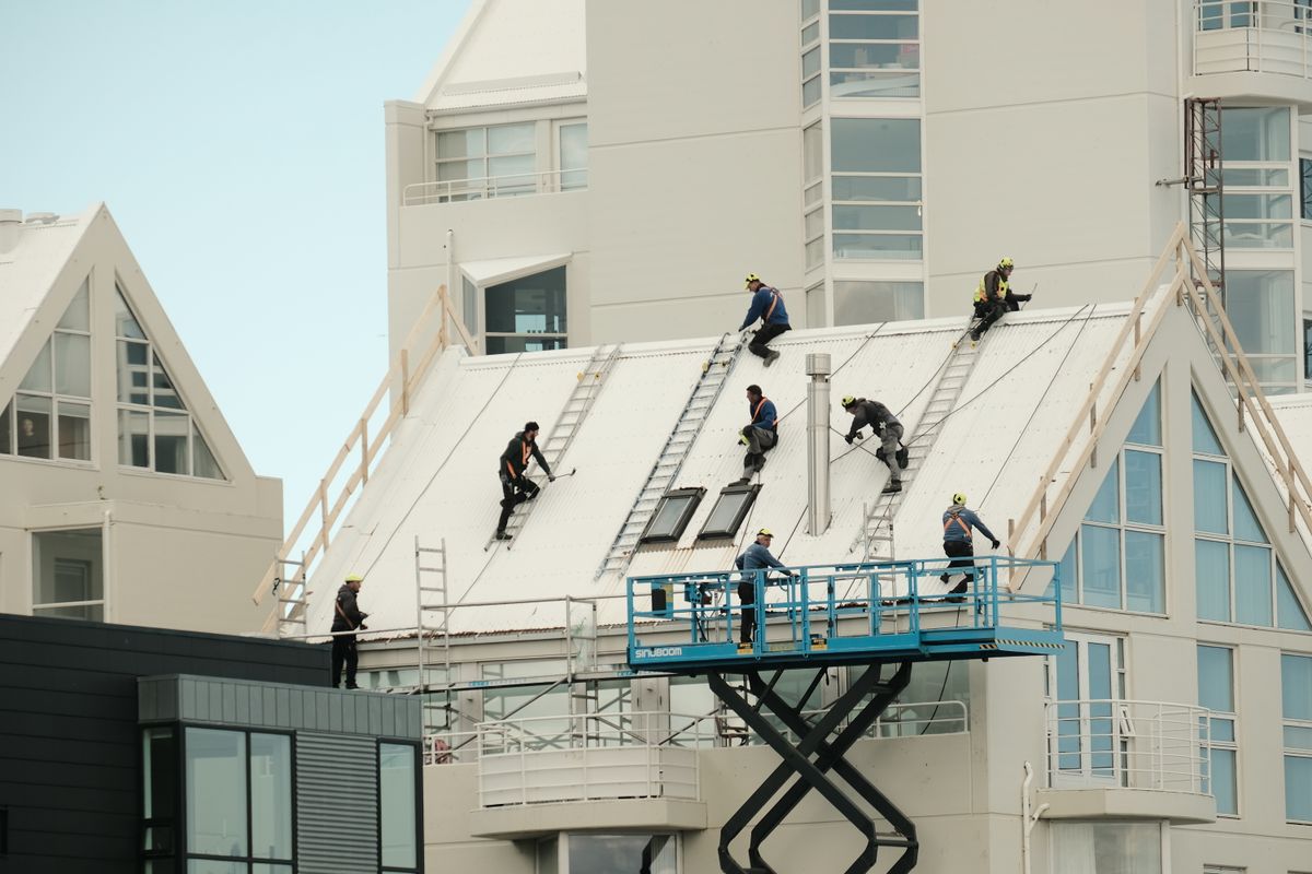 Roofing repair crew on a scissor lift working on a multi-story building