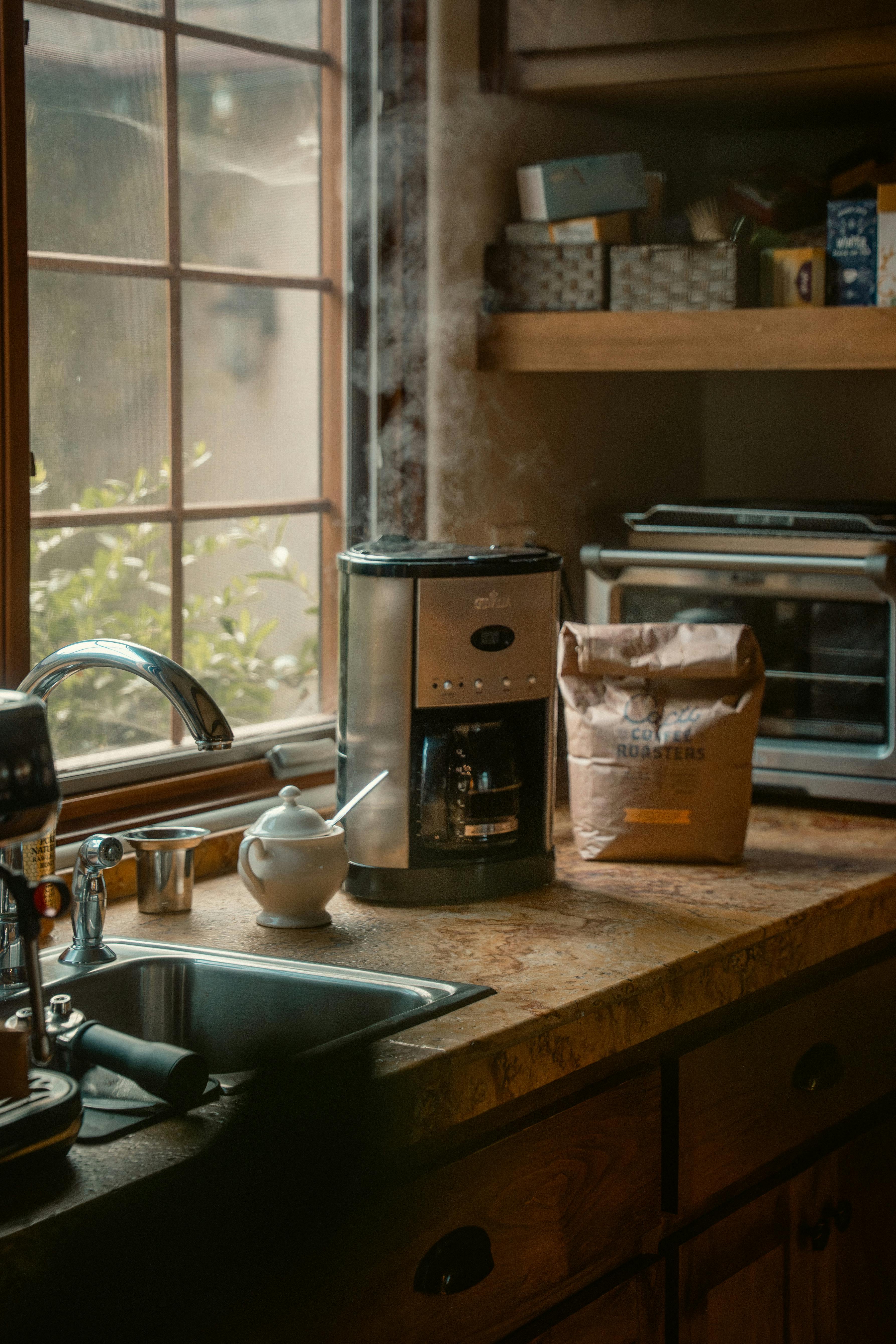 Warm kitchen interior with coffee machine, sunlight streaming through window.