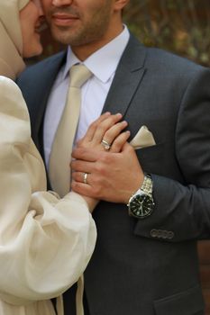 Romantic close-up of a couple dressed for a wedding, highlighting rings and formalwear.