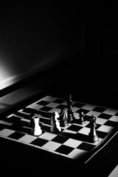 High-contrast black and white photo of a chess game in progress, capturing strategic intensity.