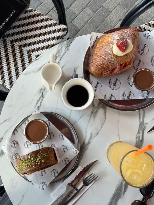 Free Elegant breakfast setup with pastries, coffee, and juice on a marble table outdoors. Stock Photo
