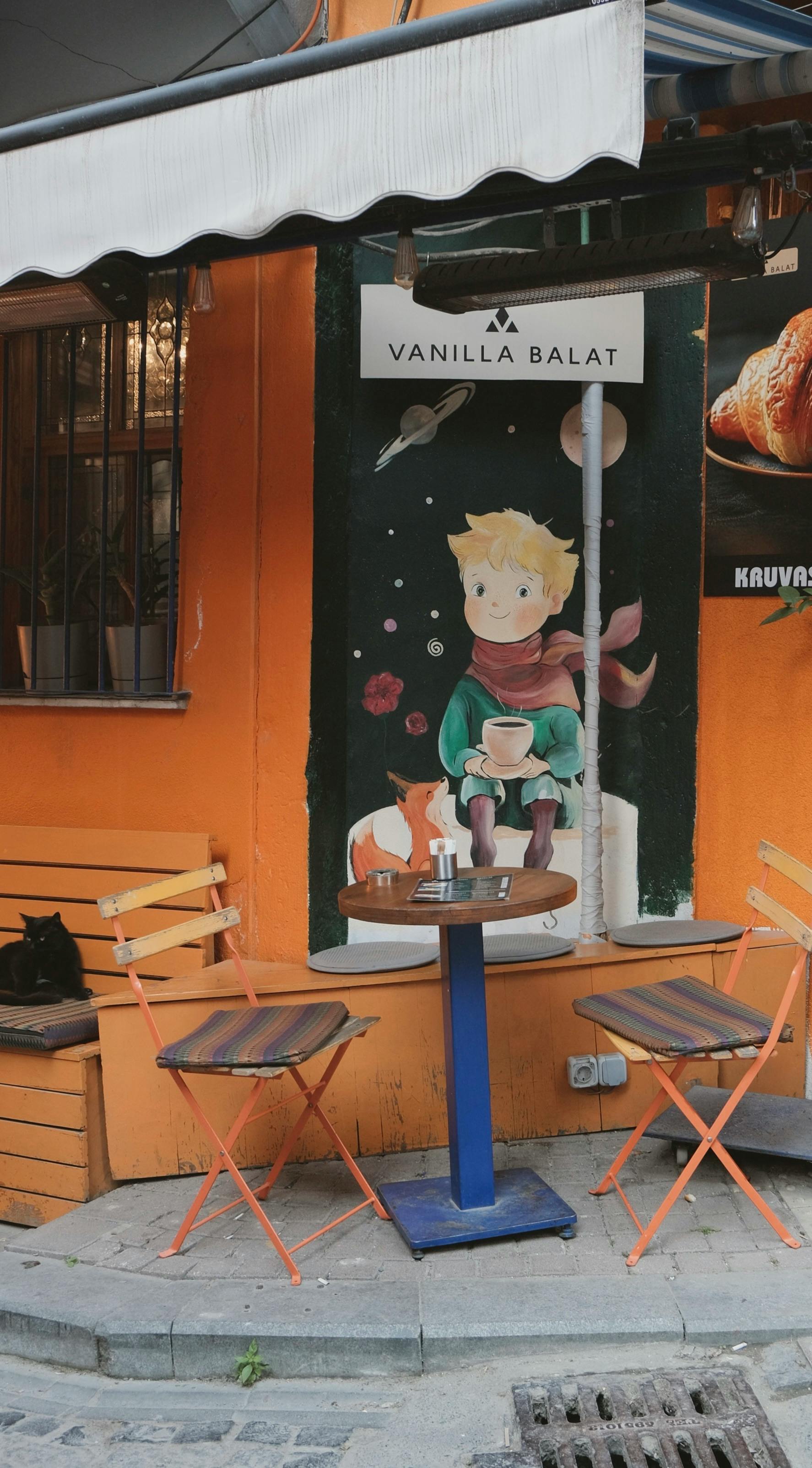 Gratuit Cafenea confortabilă în aer liber, cu o pictură murală vibrantă cu Micul Prinț și vulpea, locul perfect pentru o cafea relaxantă în Balat. Fotografie de stoc