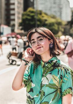 一位戴着眼镜的年轻女子在充满活力的城市环境中摆姿势