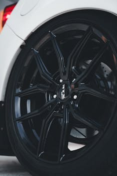 Detailed close-up of a sleek black alloy wheel on a white car, showcasing modern automotive design.