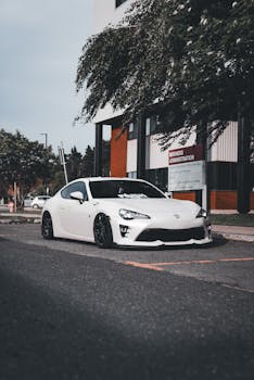 A sleek white sports car parked in a city street, showcasing modern design and style.