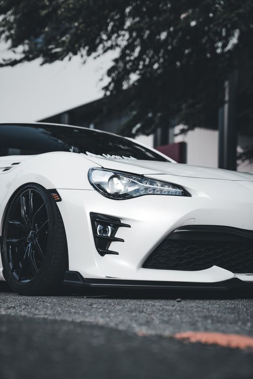 Free Close-up of a stylish white sports car parked in an urban environment, showcasing modern automotive design. Stock Photo