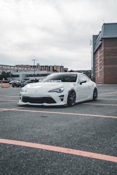 A stylish white sports car parked in an empty urban lot, showcasing modern automotive design.
