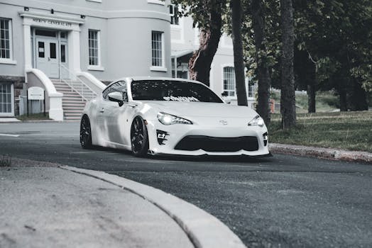 Stylish white sports car parked near a classic building, showcasing sleek design and urban elegance.